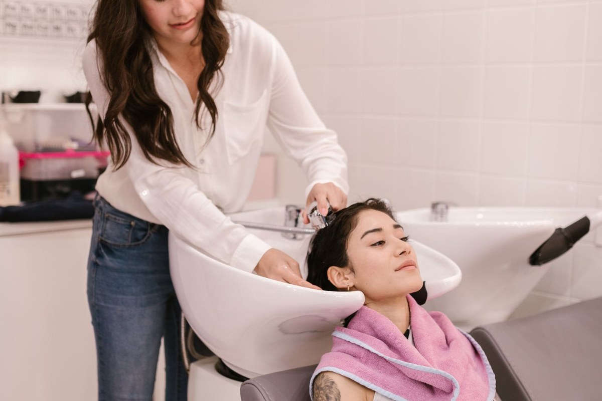 Hairdresser washing a client's hair at a salon shampoo bowl