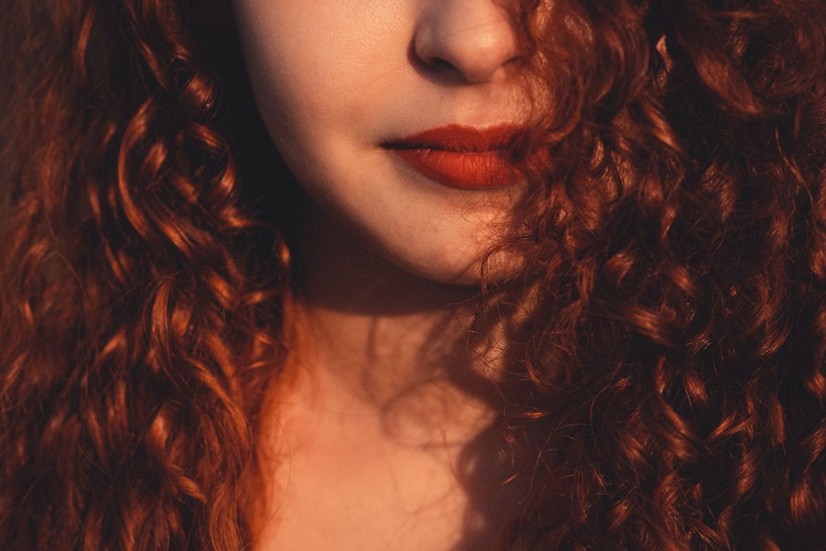 Close-up of tight auburn curls catching the light