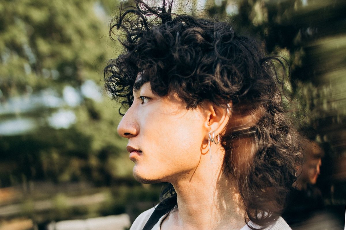 Side profile of a young man with natural curls outdoors