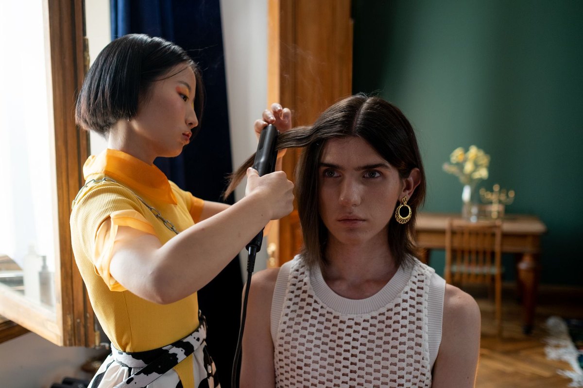 A hairdresser flat-ironing a client's hair section by section in a salon — the stage of Japanese hair straightening that takes the most time and sets the price