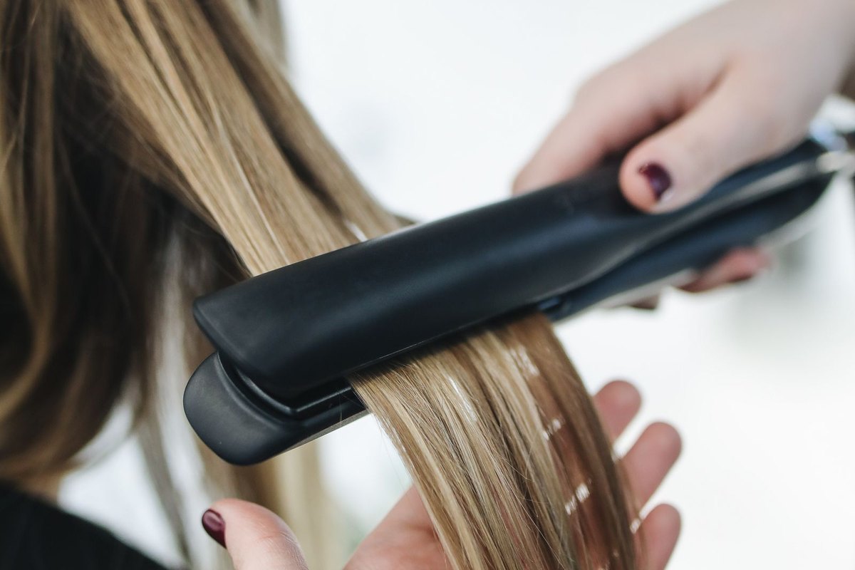 Close-up of a flat iron passing through a section of long hair