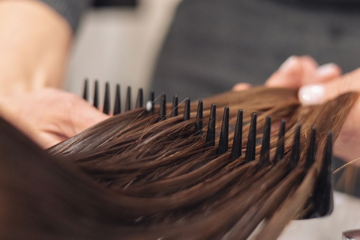A hairdresser combing through wet hair over a basin