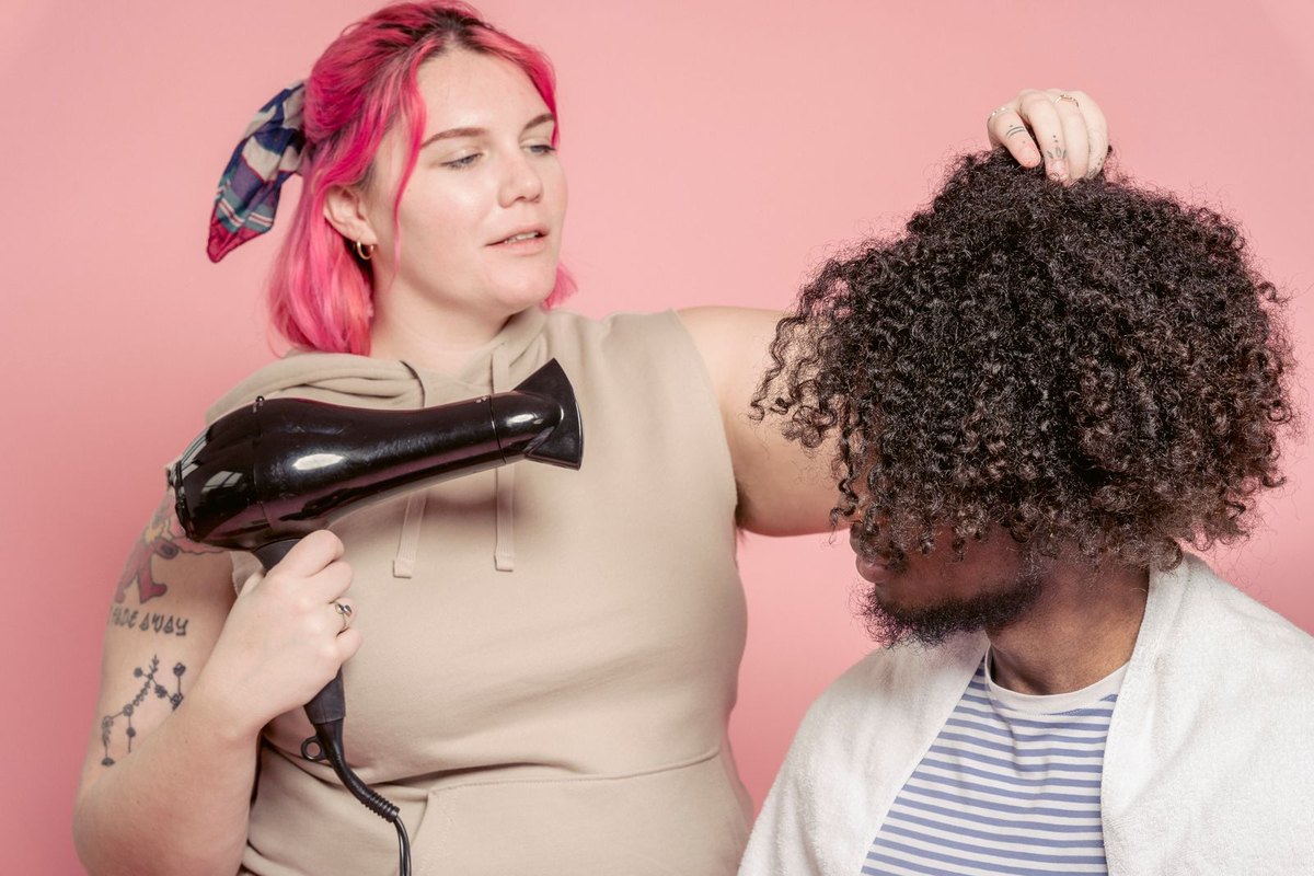 A hairdresser drying tight curls with a blow dryer