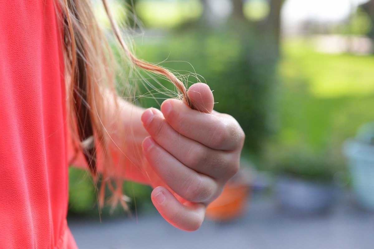 Fingers holding a single strand of hair