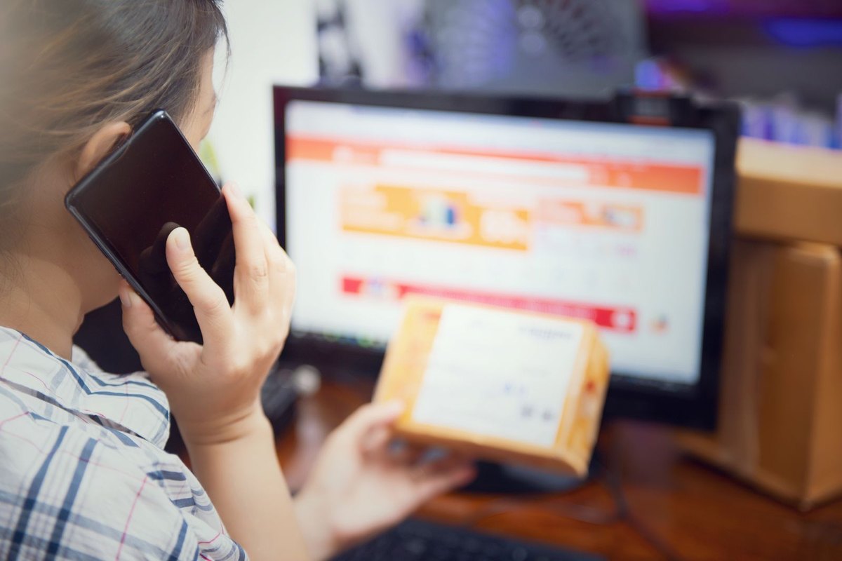 A person comparing products on a laptop while holding a phone