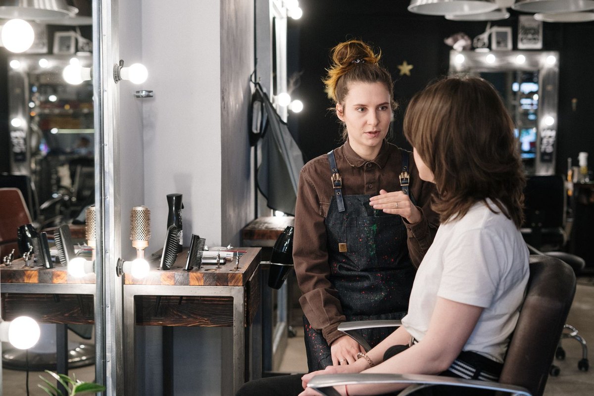 A stylist talking with a client at the salon mirror