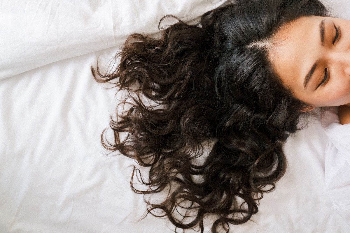 A woman asleep with her long hair spread loose across the pillow