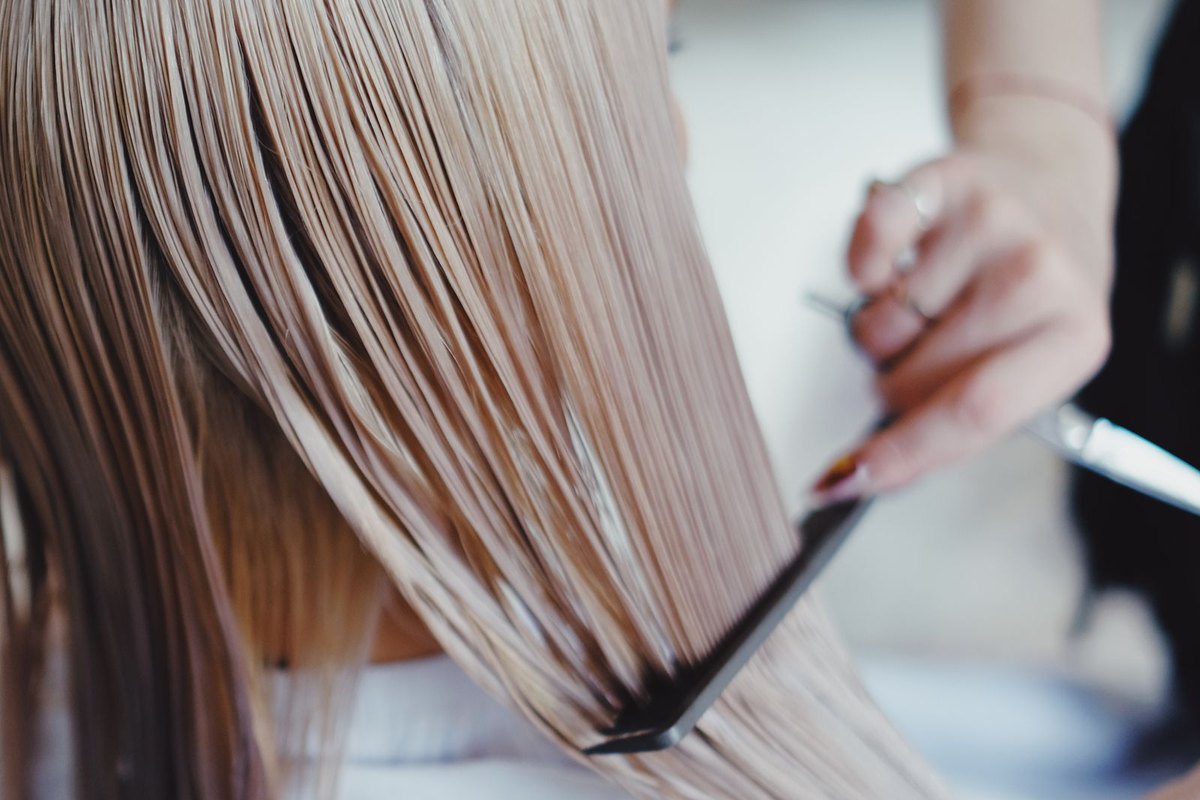A stylist smoothing a section of straight hair with a flat iron