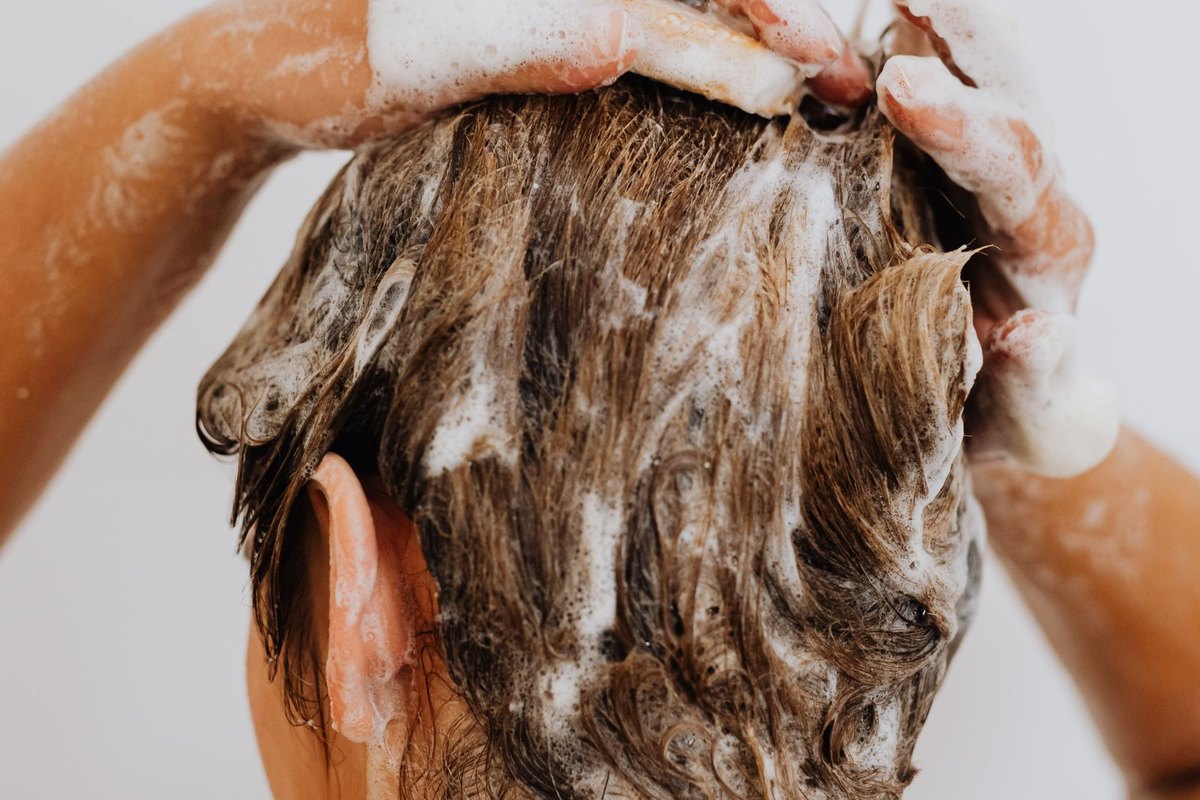 Woman rinsing shampoo foam out of her hair in the shower