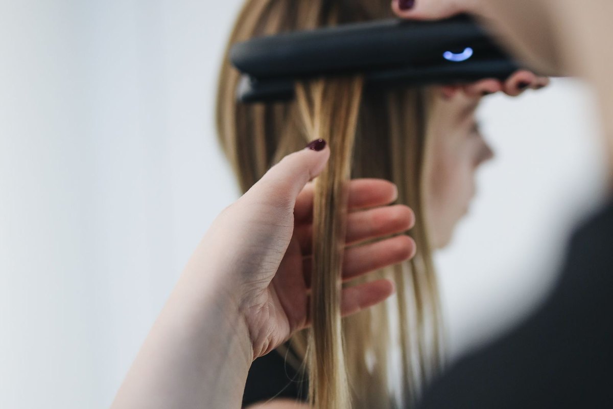 A stylist pressing a flat iron through straightened hair