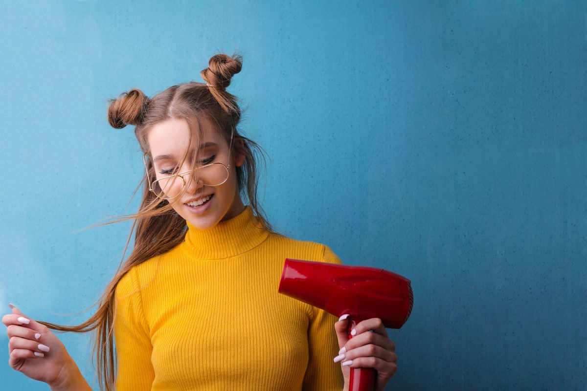 Woman blow drying long hair at home with a hair dryer